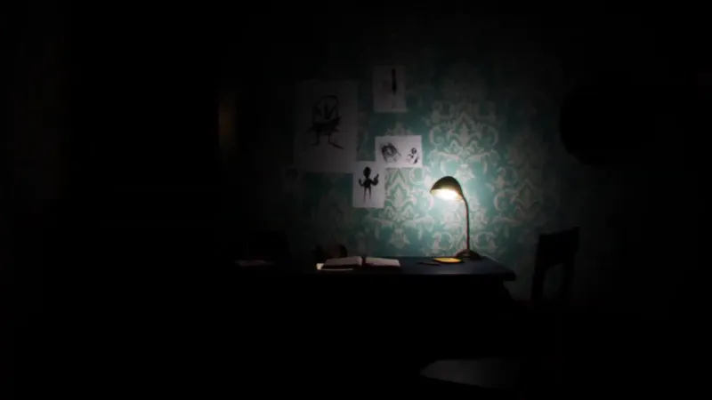 A wooden desk illuminated by a lamp in a dark room with creepy children's drawings